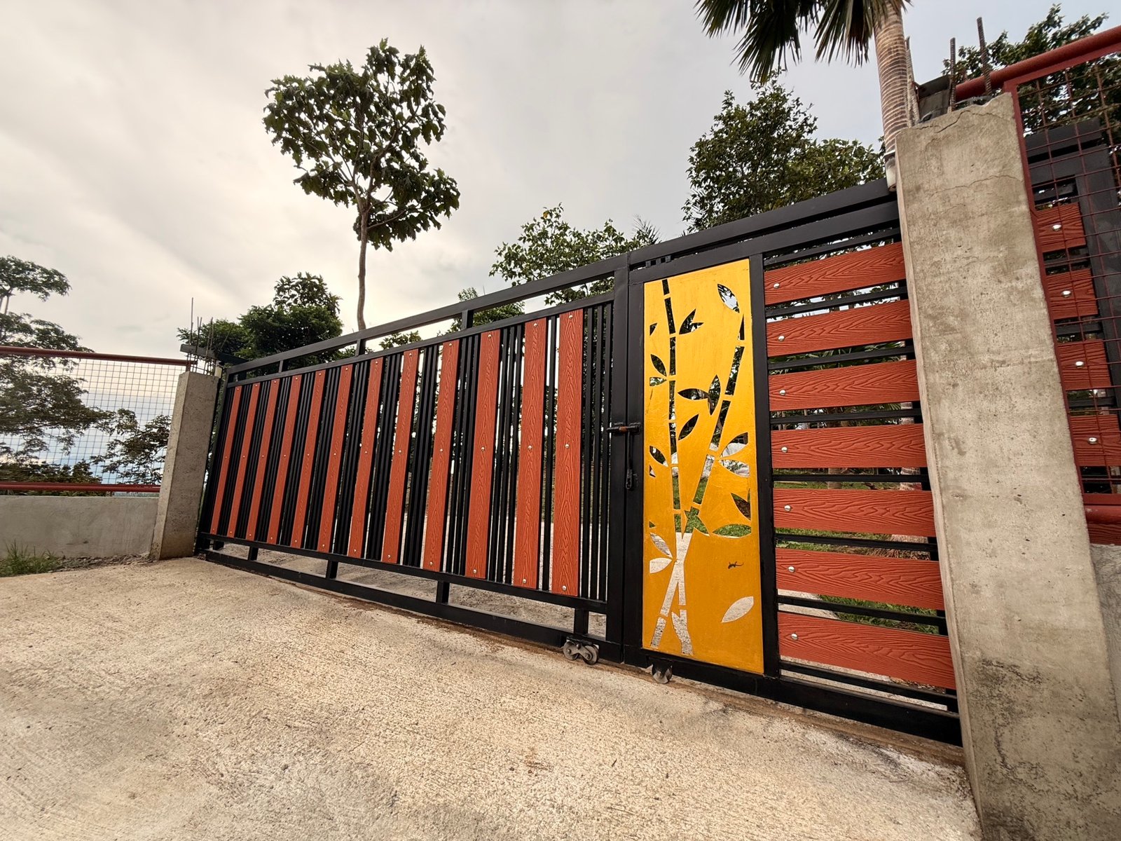 The black steel farm gate with its gold bamboo cut-out panel
